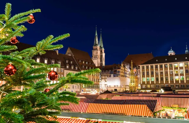 De Christkindlesmarkt in Nürnberg bij avond, met de torens van de Frauenkirche