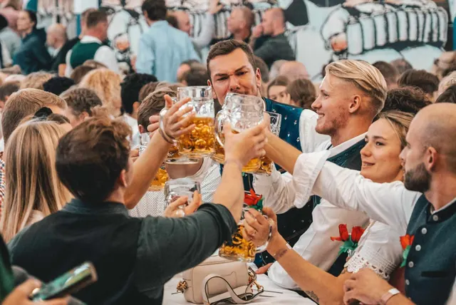 Proosten met maßkrügen in een feesttent